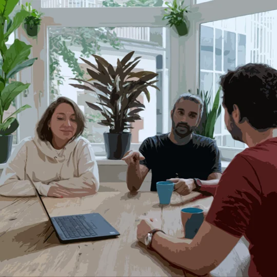 Three roommates talking around a kitchen table with a laptop, used as the roommate agreement hero image